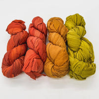 Five fabric bundles in red, orange, and green arranged in a row on a white background.