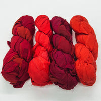 Five twisted fabric bundles in red and orange laid side by side on a white background.