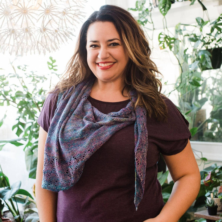 Model wearing lace weight silk shawl in tidal pool with potted greenery in the background