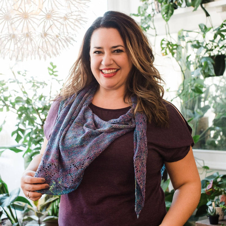 Model wearing lace weight silk shawl in tidal pool with potted greenery in the background