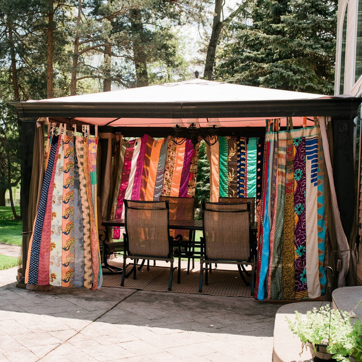 Outdoor sari silk curtains hanging around a pergola.