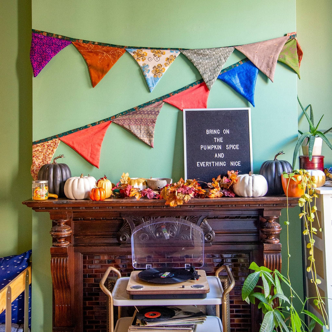 Bunting banner hangs over a fire place with pumpkins and message board saying bring on the pumpkin spice and everything nice.