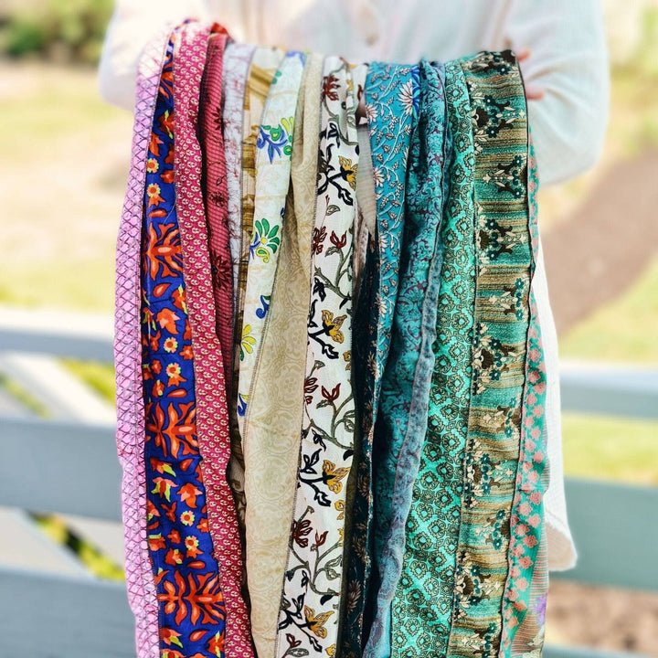 A person holding a multicolored scarf made from reclaimed sari fabric.