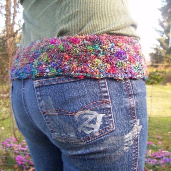Side view of a woman wearing a thick belt made of multicolored yarn outside