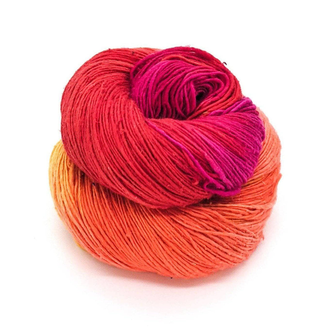 Lace weight silk yarn in color way color surge (orange, yellow and pink) in front of white background.