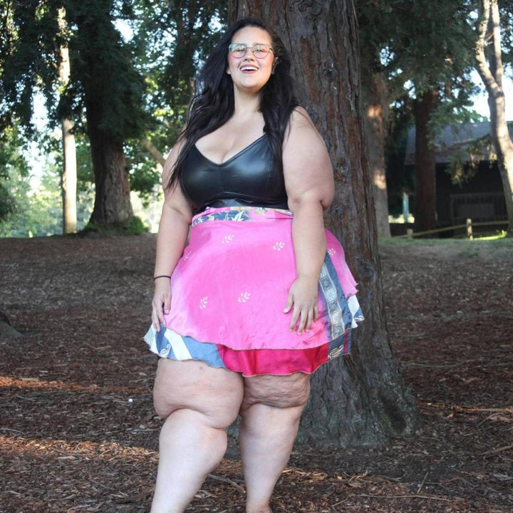 Goddess Model standing in a wooded area wearing a pink sari wrap mini skirt.