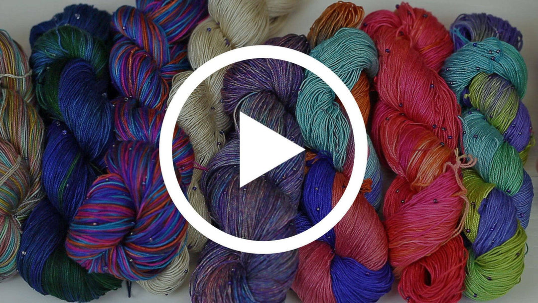 A hand beaded silk yarn with a play button in the middle.