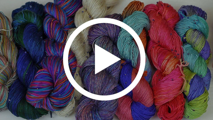 A hand beaded silk yarn with a play button in the middle.