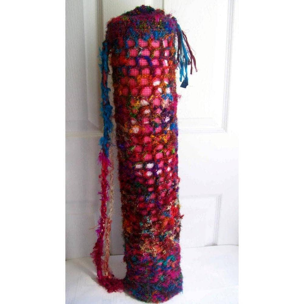 Yoga Mat Carrying Bag crocheted in multicolor red yarn leaning against a white wall