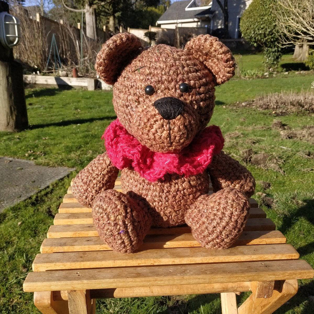 Brown Bear Amigurumi Crochet stuffed animal sitting on a wooden table on grass