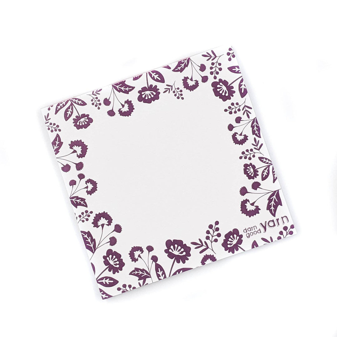 White paper note pad with a purple floral boarder on a white background