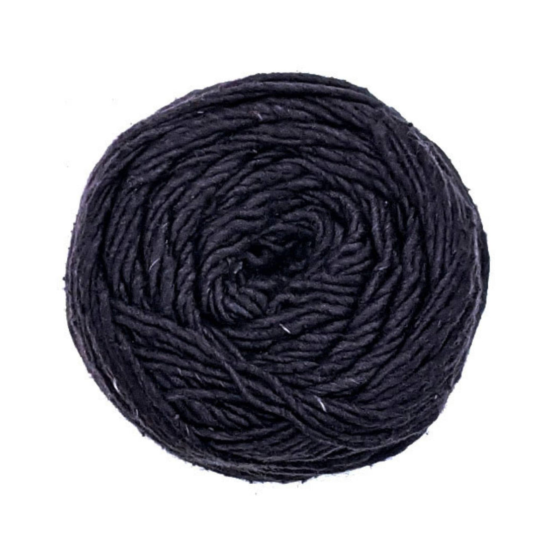 cake of silk roving worsted weight yarn in the colorway black in front of a white background.
