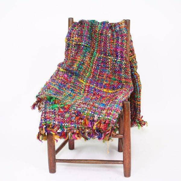 Multicolored woven blanket draped over a wooden chair on a white background