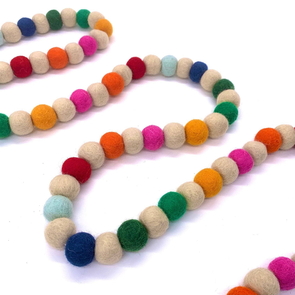 Multi Color Felt Ball Garland laying on a white background.