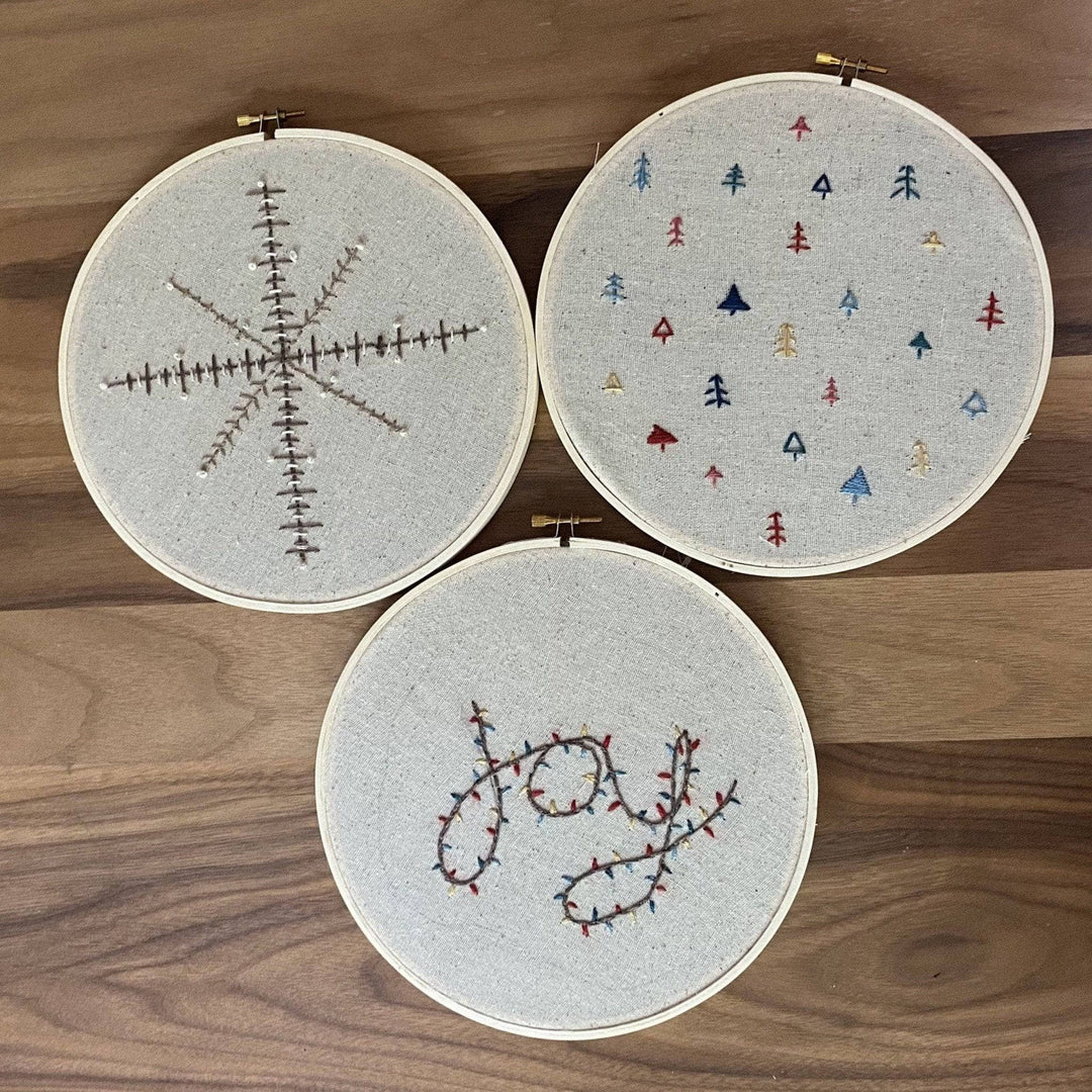 3 holiday embroidery hoops on a wood background