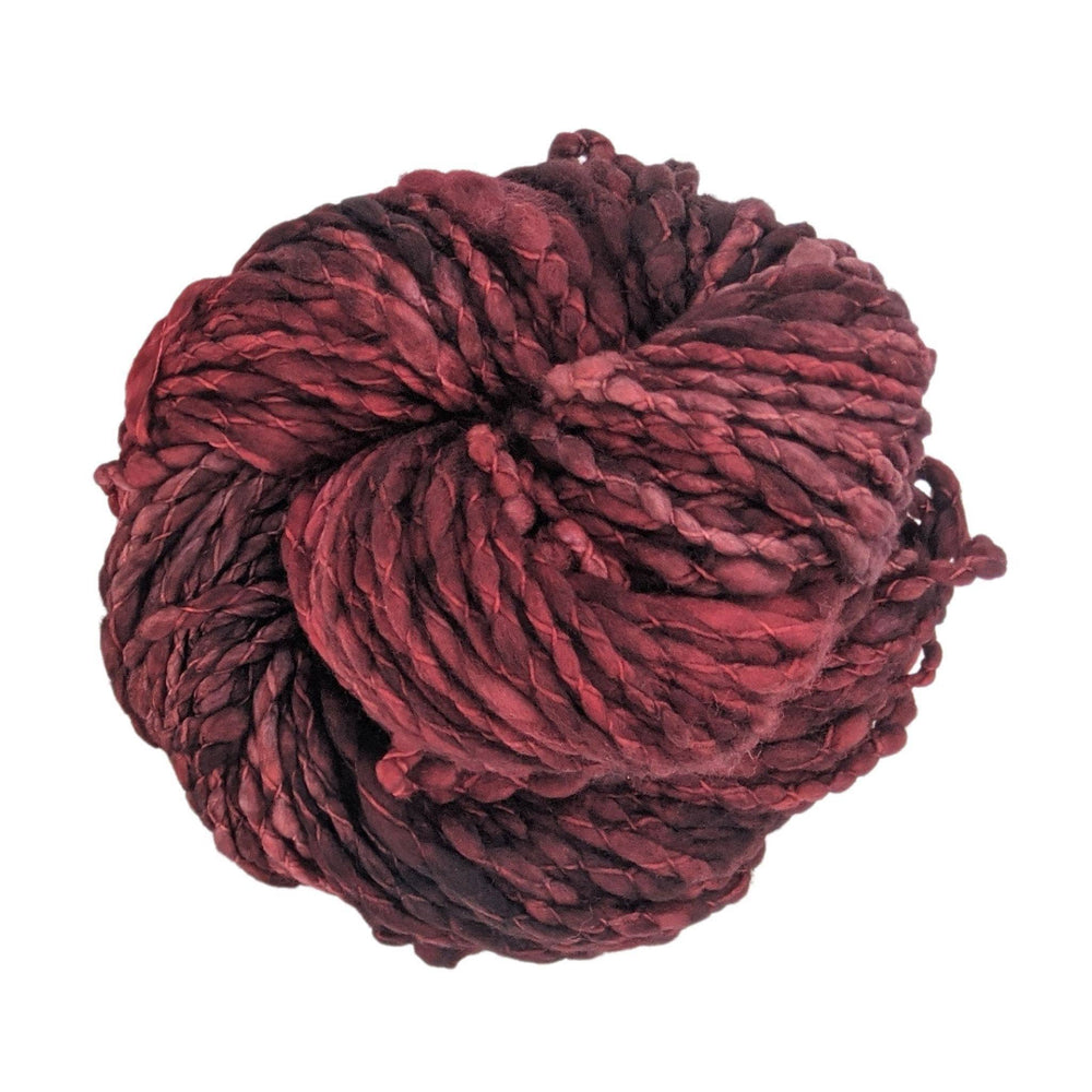Skein of tonal dark red yarn in front of a white background. 