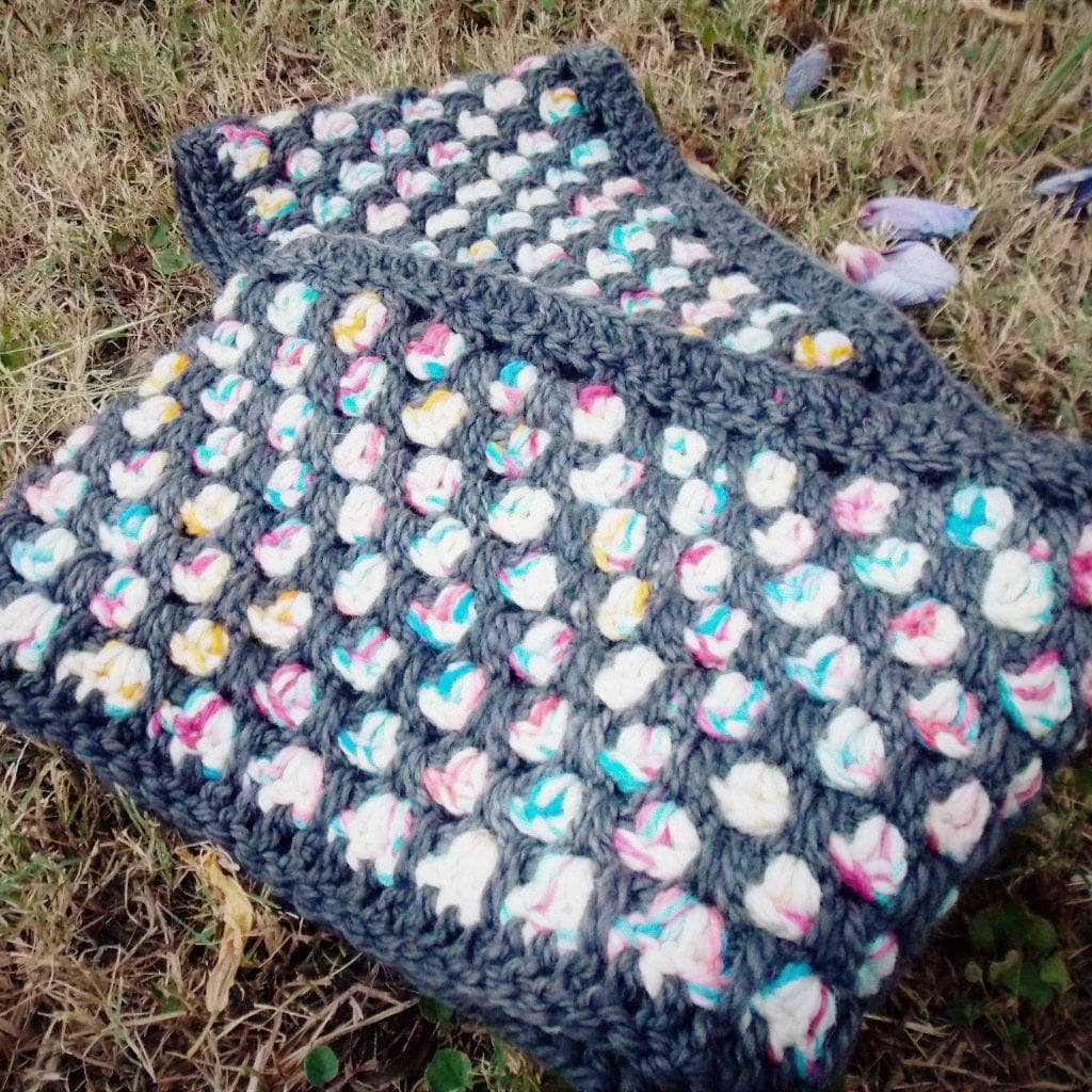 shawl with black and multicolored dots over grass