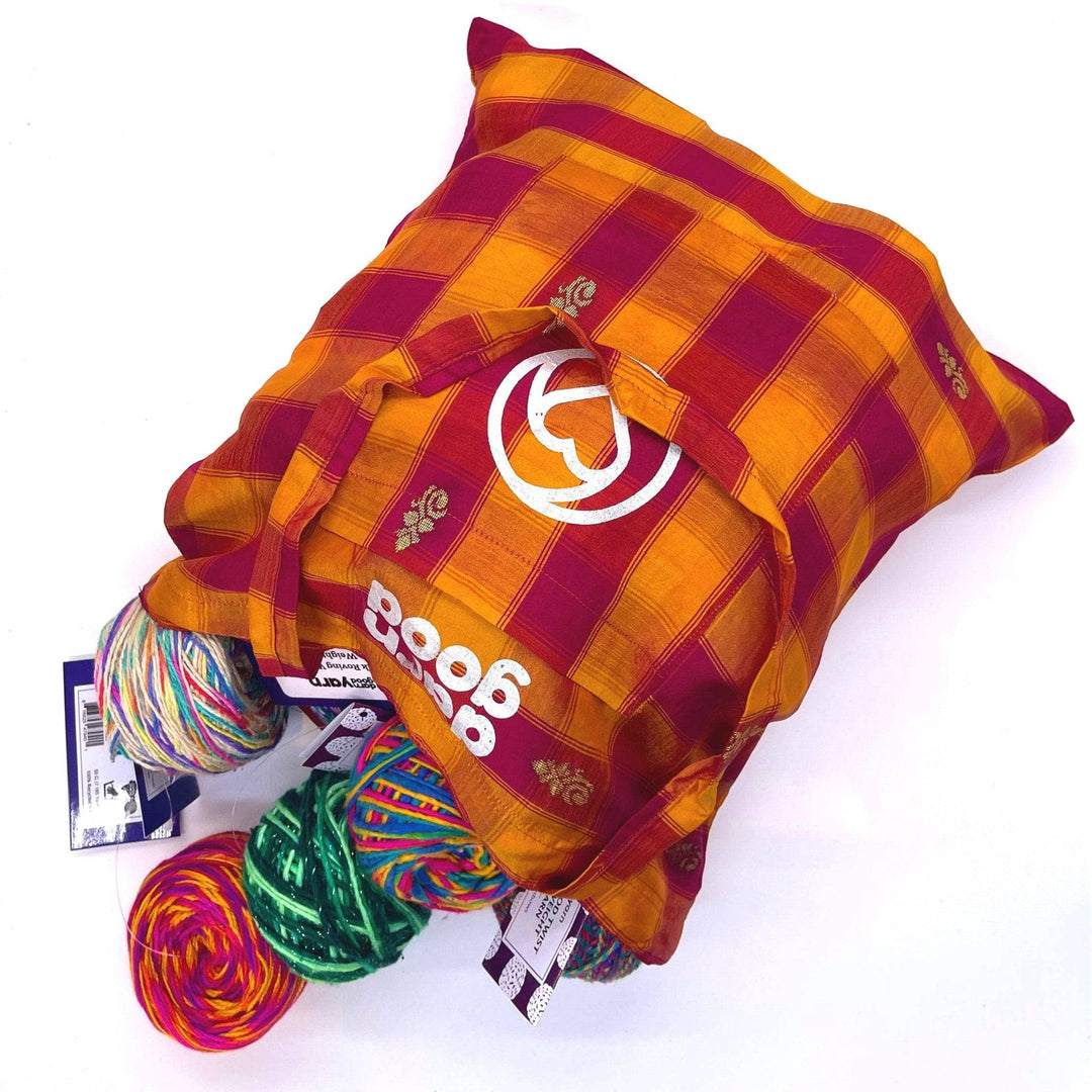 A Red and Orange Checkered Sari Silk Tote laying on a white background. Theres a bunch of different yarns spilling out.