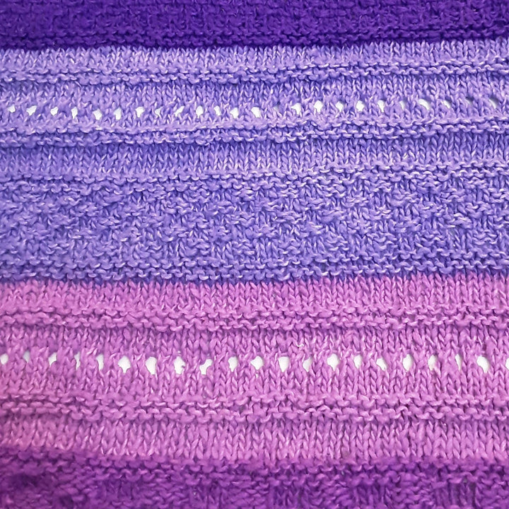 closeup of stitched in ombre stitch sampler shawl purple in front of a white background.