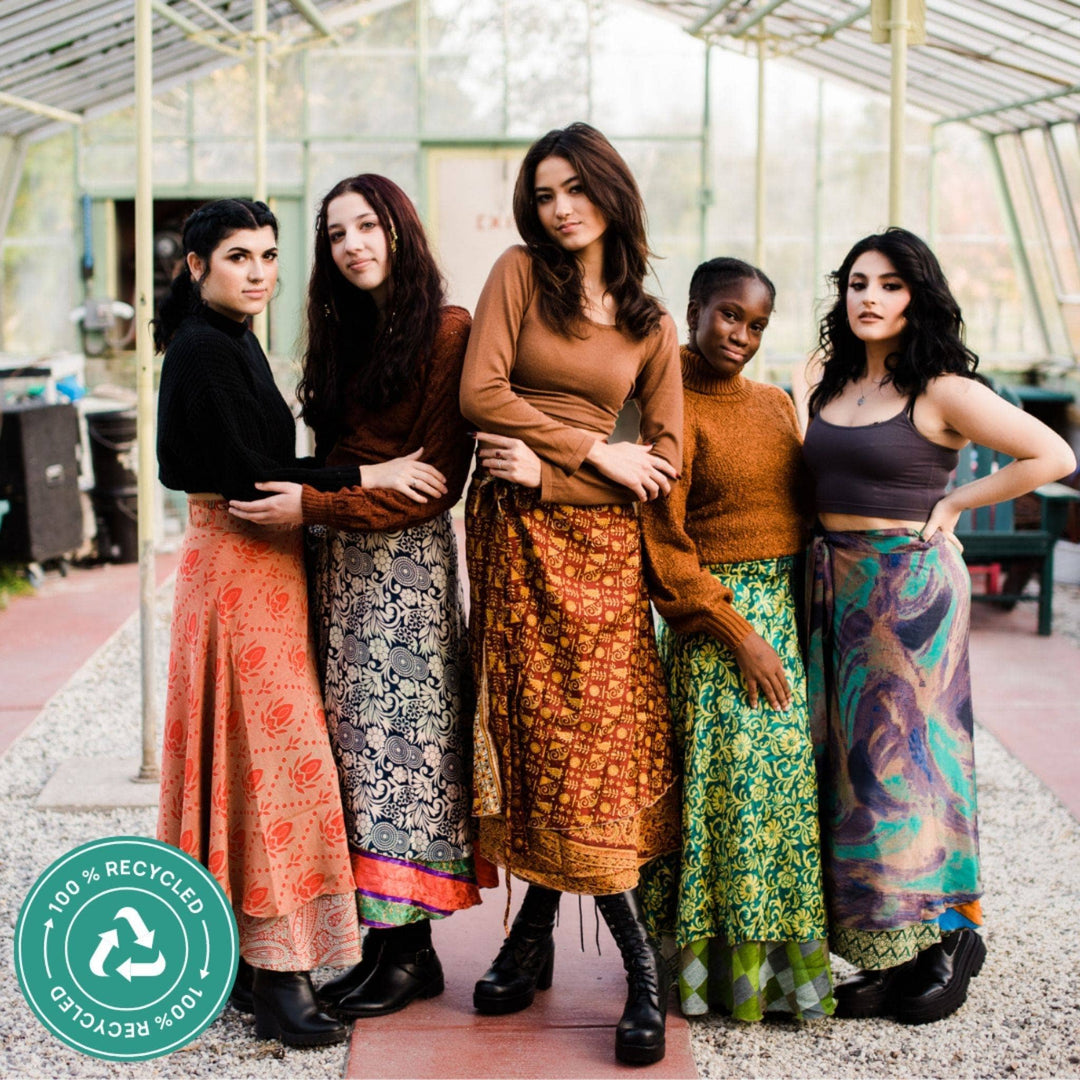 5 models wearing women's ankle sari wrap skirts while standing in a greenhouse.