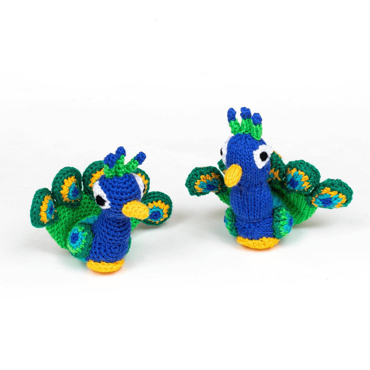 Crochet (left) and knit (right) versions of amigurumi peacock sitting next to each other in front of a white background. 