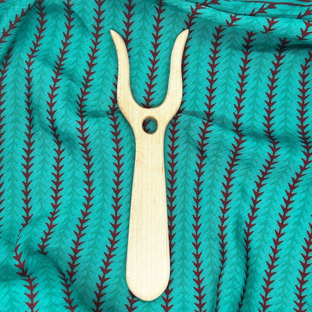 Red maple wooden Lucet on turquoise fabric with triangle stripes on fabric