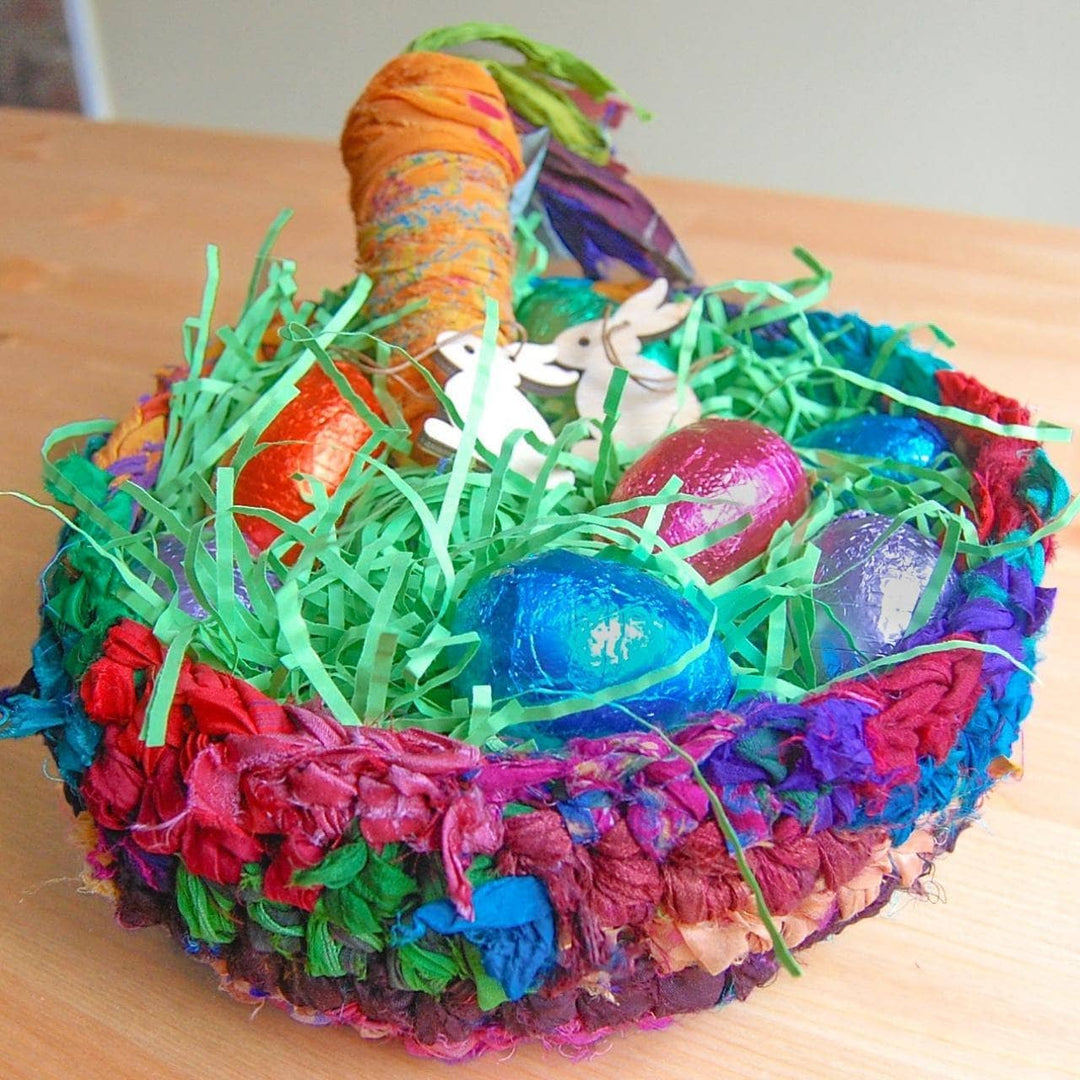colorful basket of ribbon yarn with confetti. a carrot and easter eggs inside