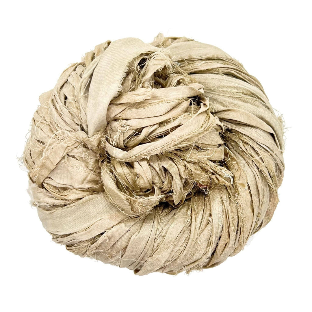 A skein of reclaimed sari silk ribbon in the colorway 'champagne' sitting on a white background.
