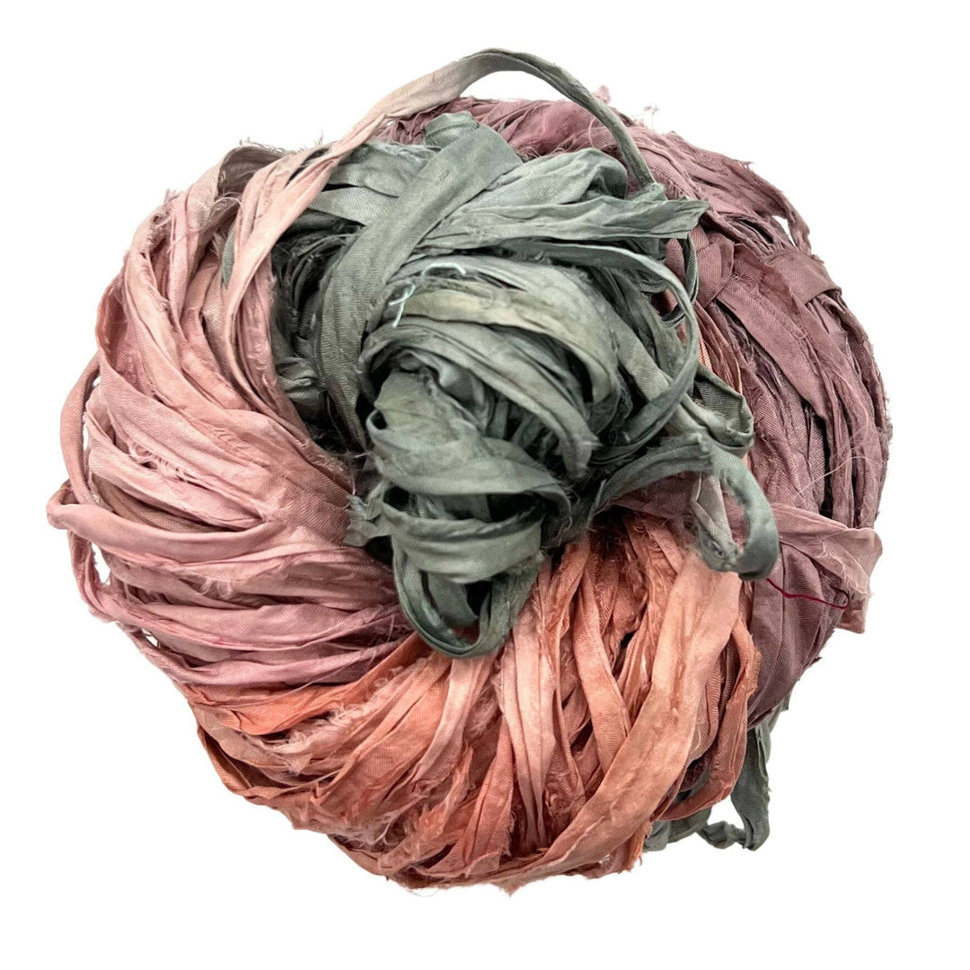 A skein of reclaimed sari silk ribbon in the colorway 'dusty rose' sitting on a white background.