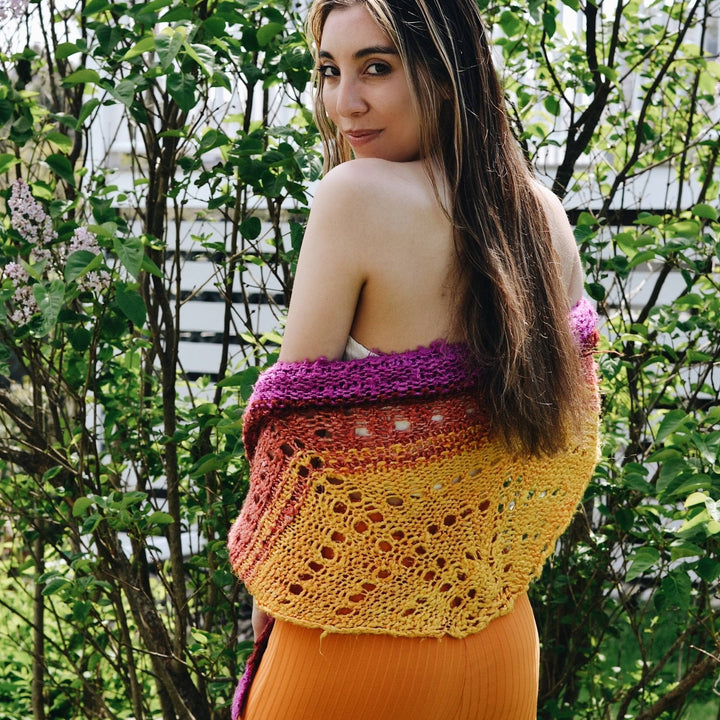 model wrapped in that sunset was bananas shawl with greenery in the background.