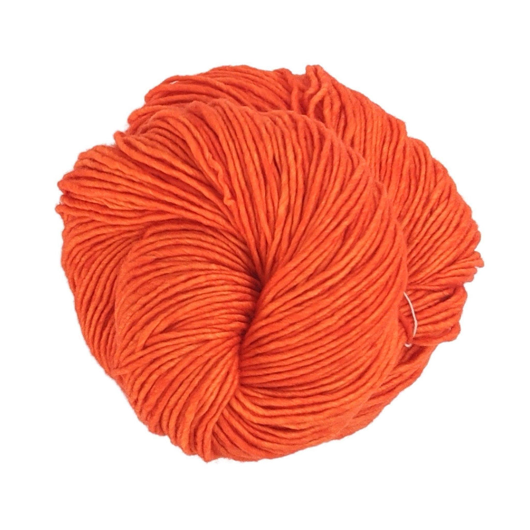 skein of single ply orange malabrigo wool yarn in front of a white background.