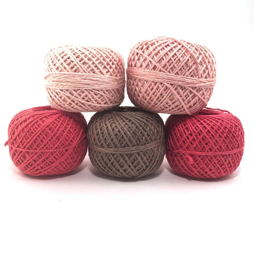 5 cakes of 2 ply recycled silk yarn in the colorway vintage rose in front of a white background. (4 shades of pink, one brown)