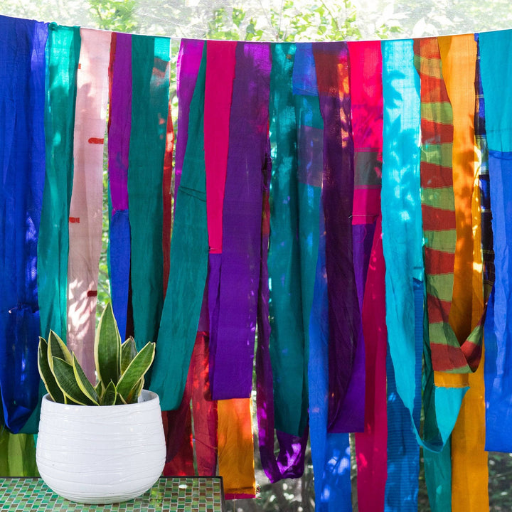 2.5" Sari silk ribbon roll unwound and strung over a clothesline with a potted plant in the foreground.