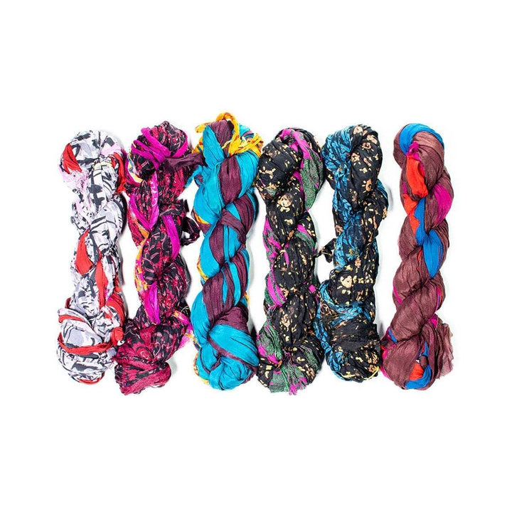 Six braided skeins of yarn with mixed patterns, prints, and bold colors.
