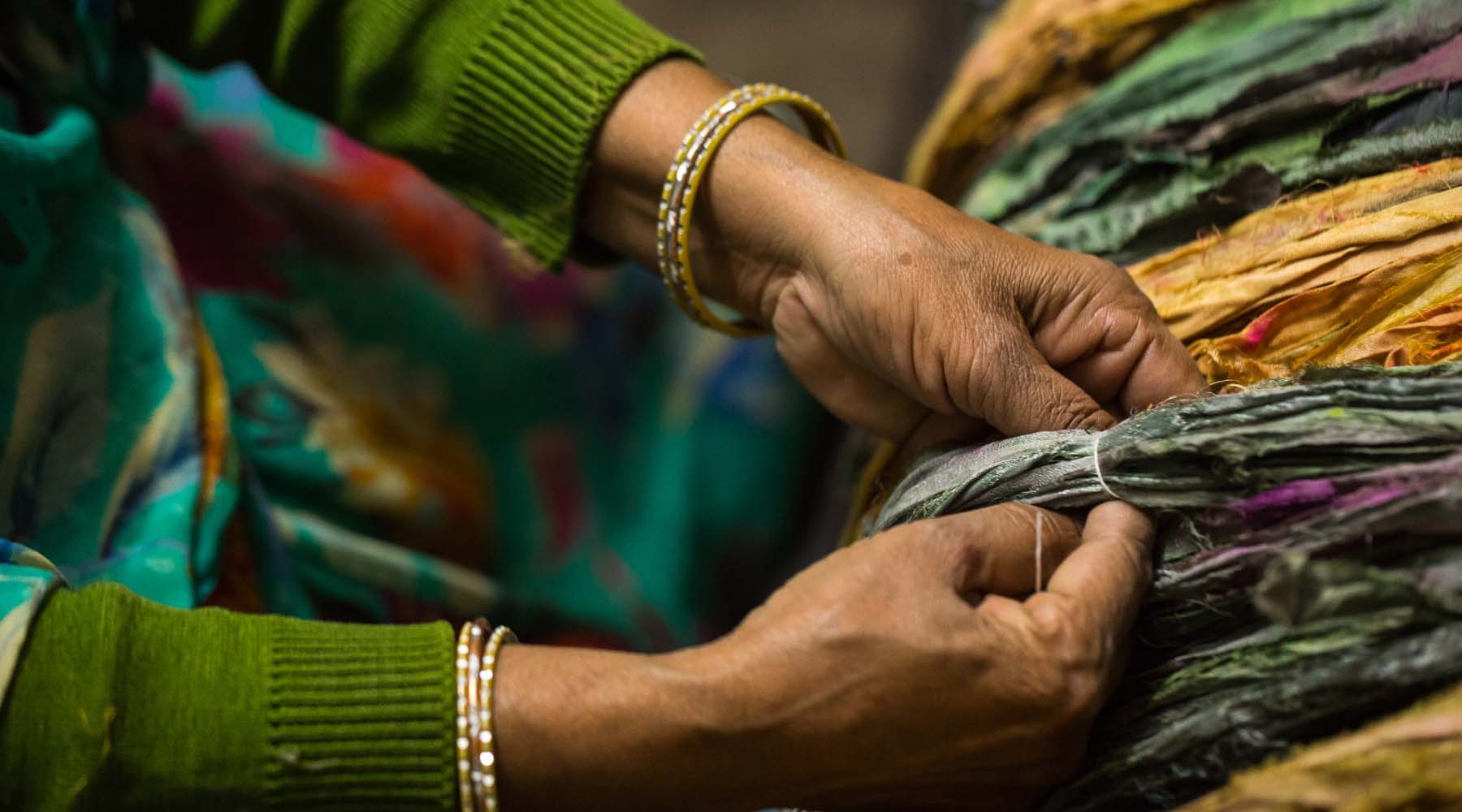 A hands working with yarn, showing careful weaving with colorful threads
