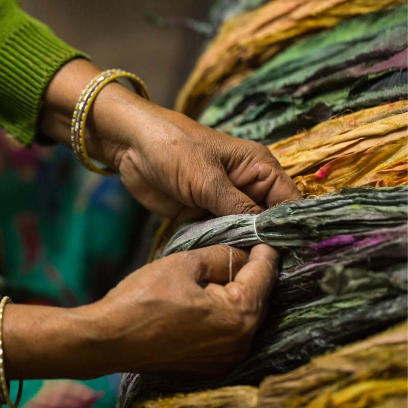A hands working with yarn, showing careful weaving with colorful threads