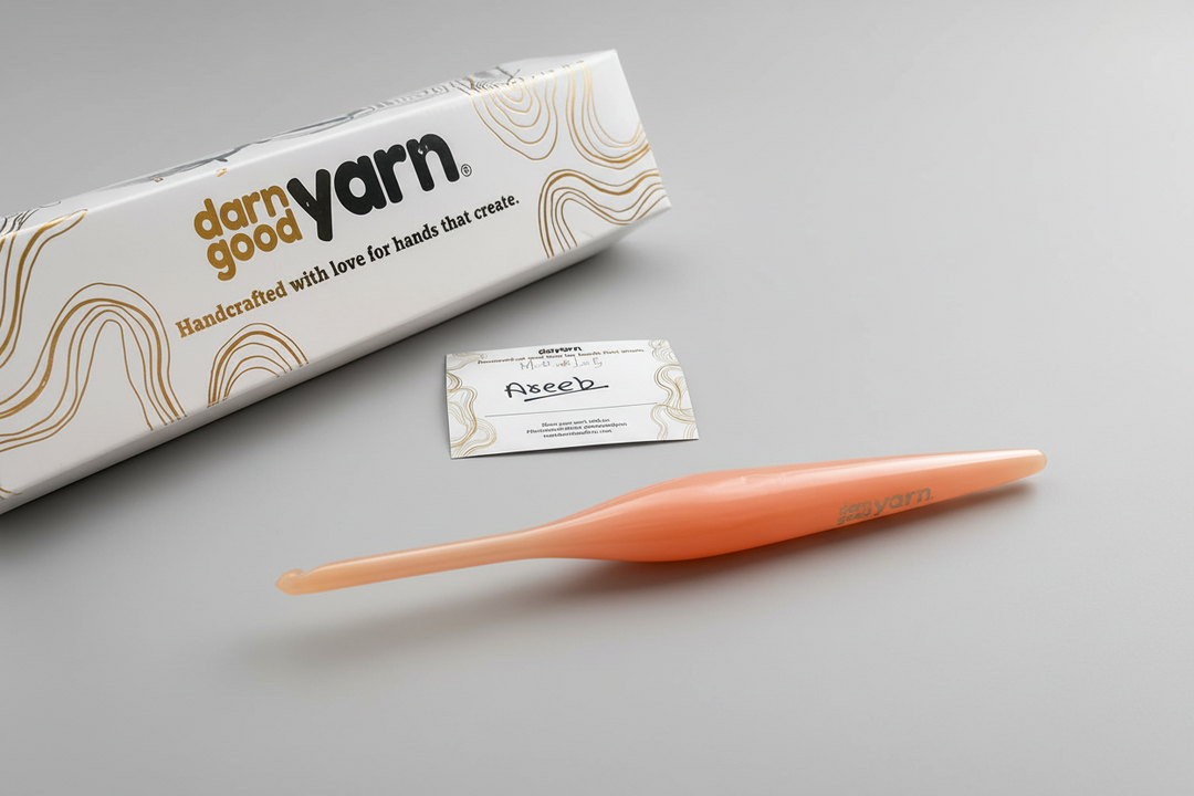 Orange crochet hook with 'darn good yarn' packaging on a light surface
