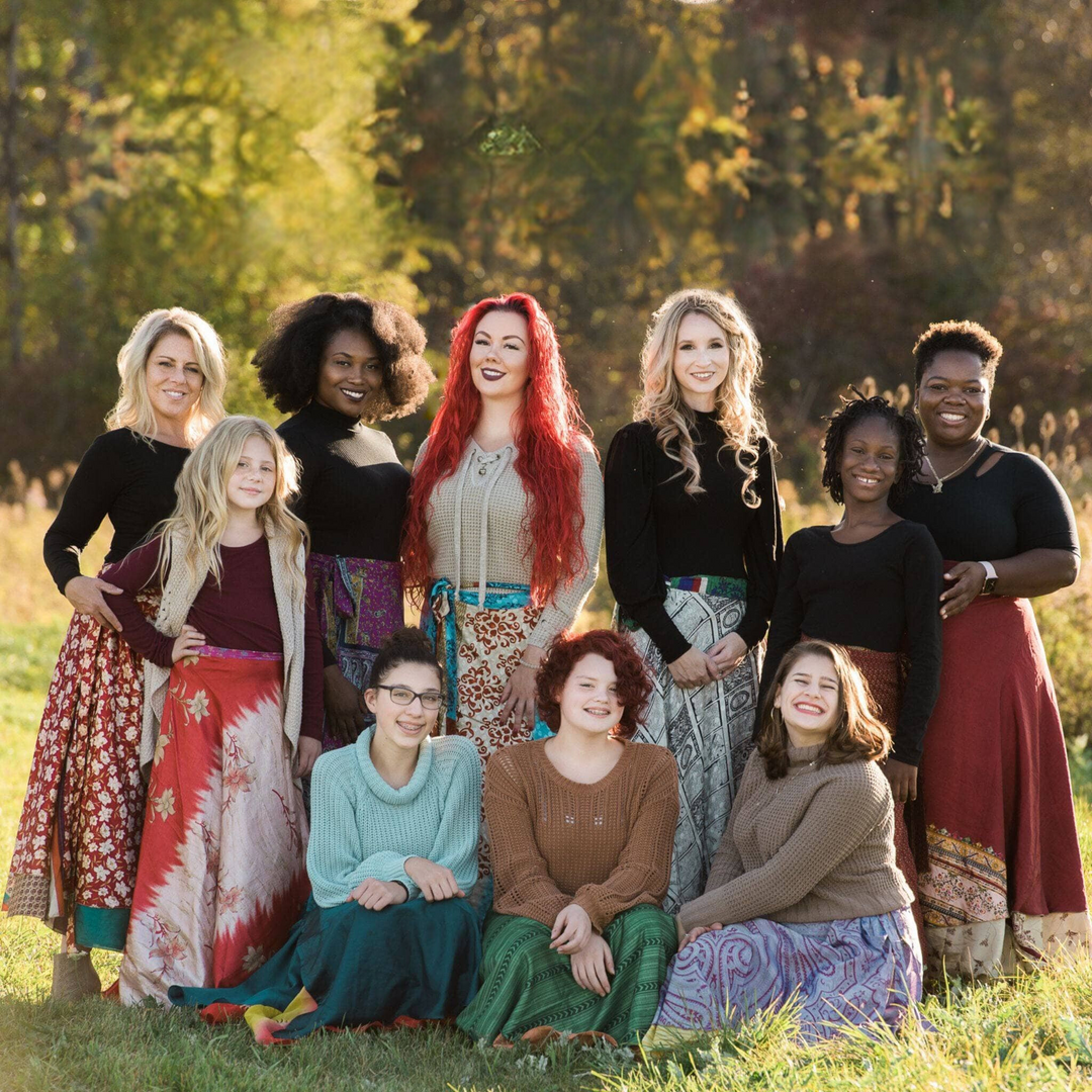 A group of smiling women wearing colorful skirts