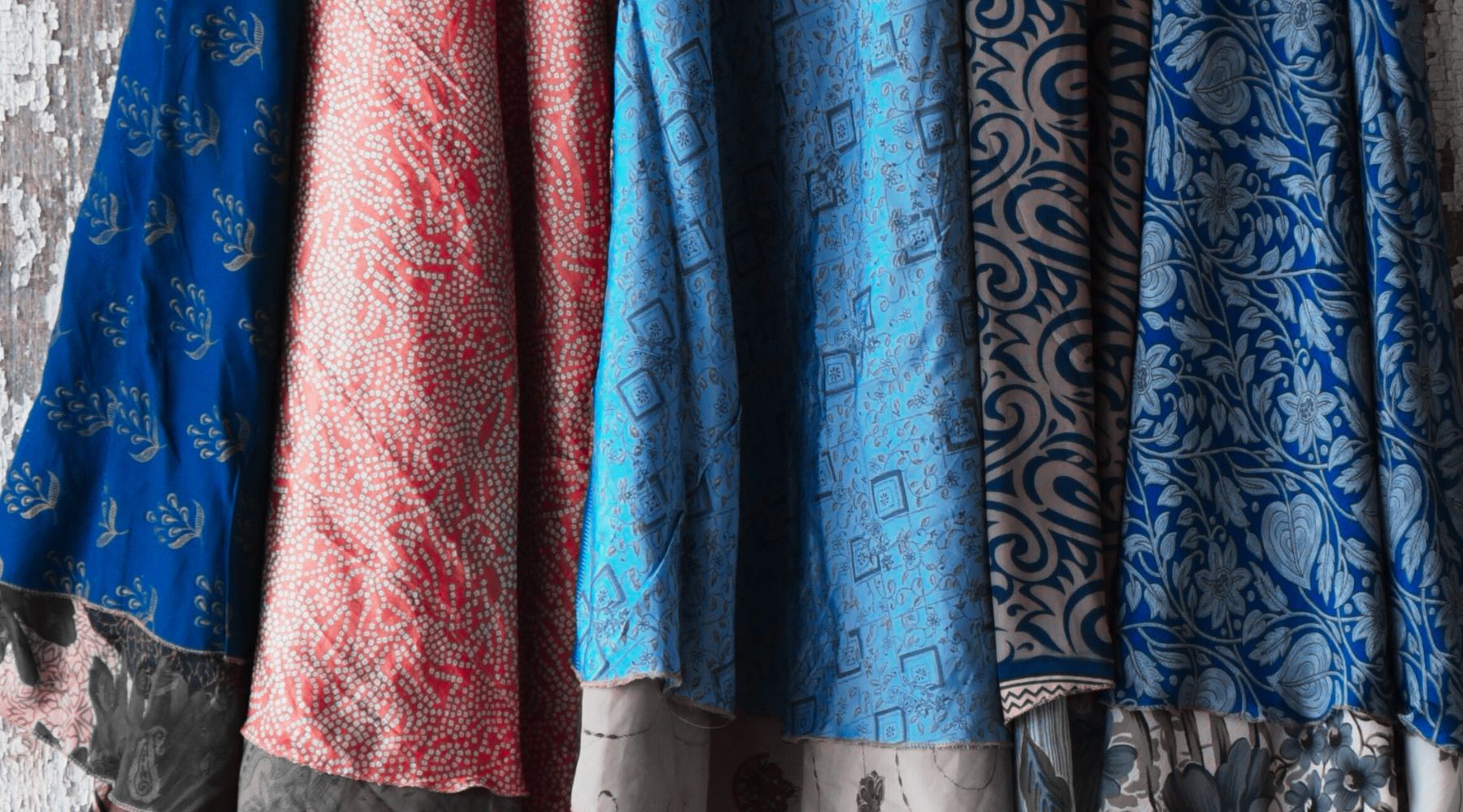 Hanging fabrics with intricate patterns in blue, red, and beige with floral designs.