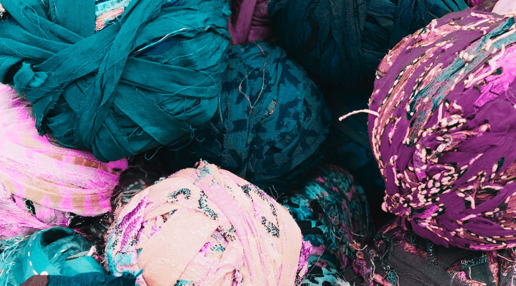 Balls of colorful, textured fabric in vibrant shades of purple, teal, and pink.