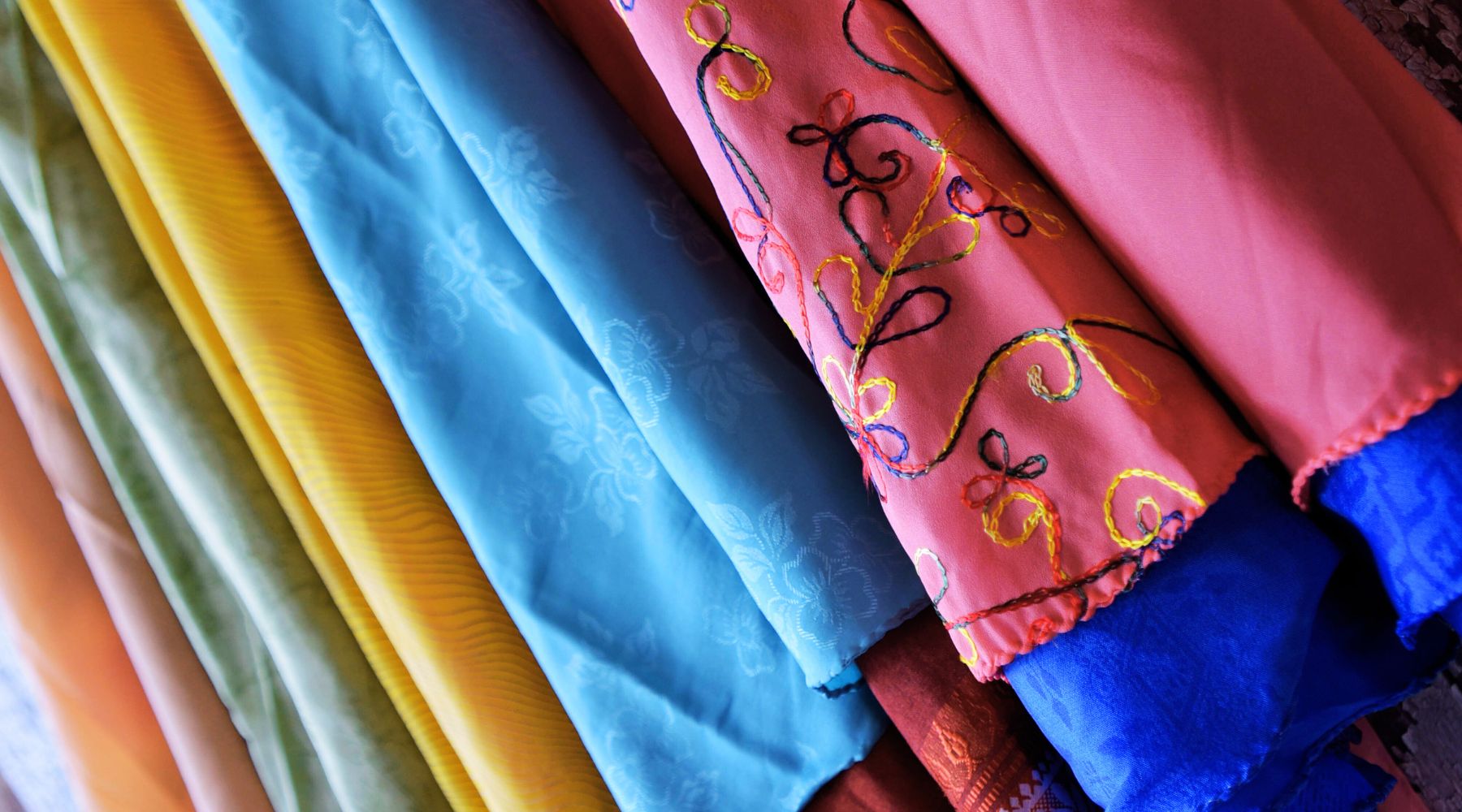 Fabrics of various colors, including pink, yellow, and blue, hanging neatly.