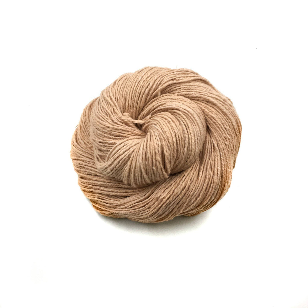 close up of yarn in the color voca peach (salmon) with a white background