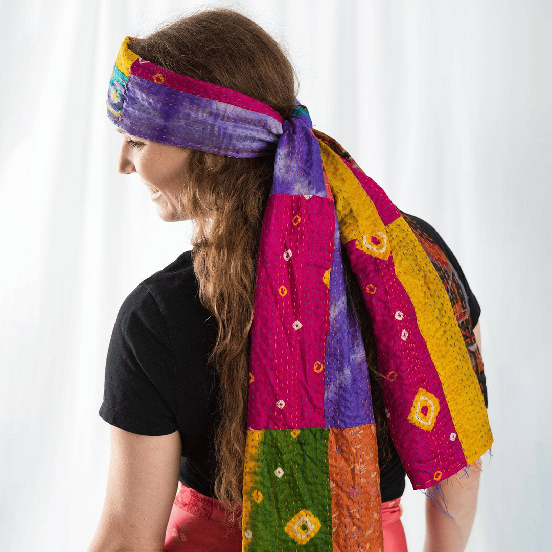 Woman wearing a vibrant patchwork scarf as a headband, posing with a side profile.