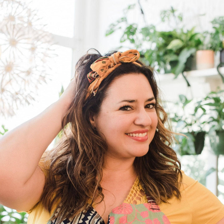 Model wearing yellow boho vintage sash accessory as a headband with a bow tied on top.