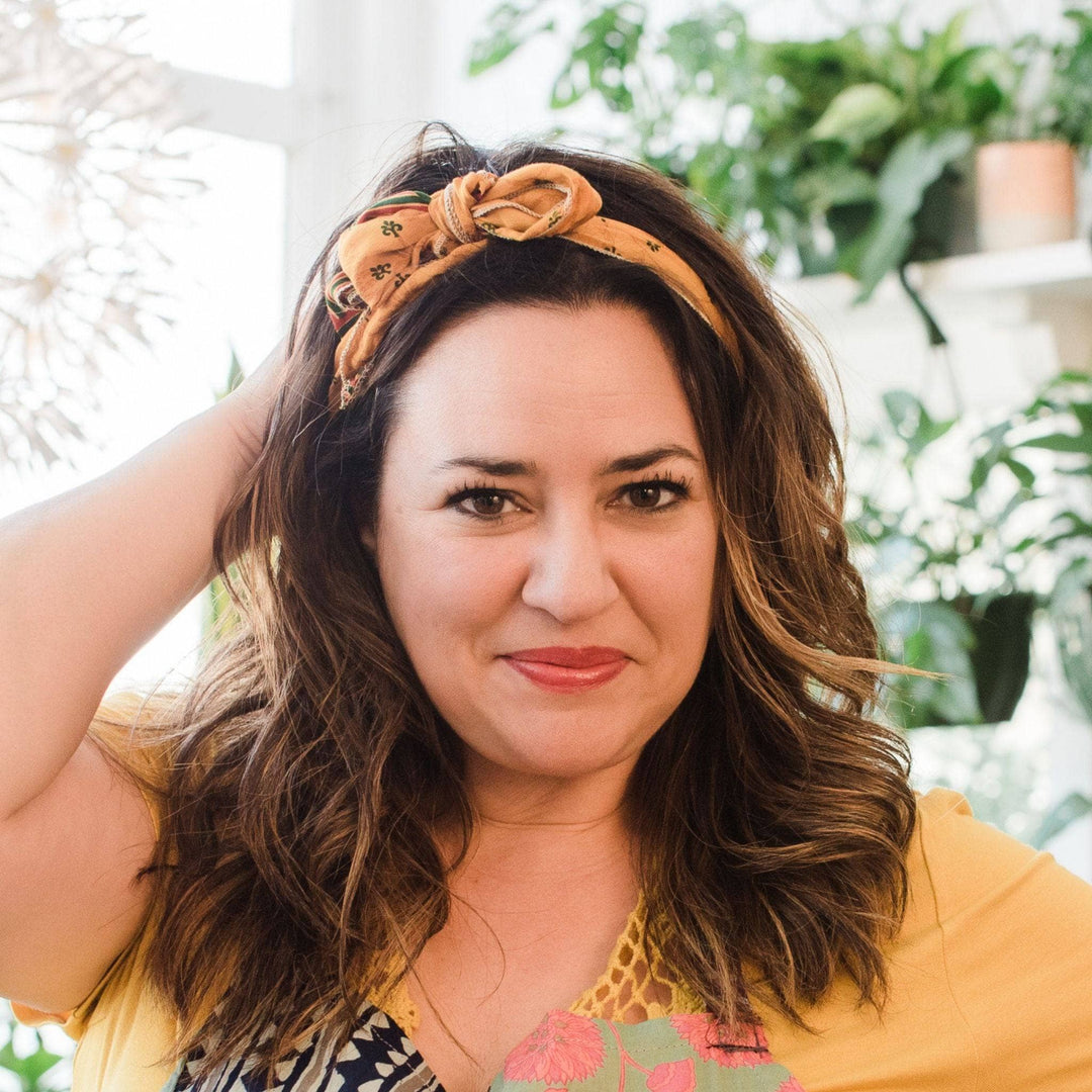 Model wearing yellow boho vintage sash accessory as a headband with a bow tied on top.