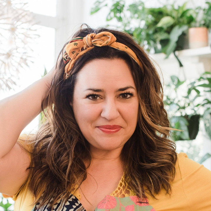 Model wearing yellow boho vintage sash accessory as a headband with a bow tied on top.