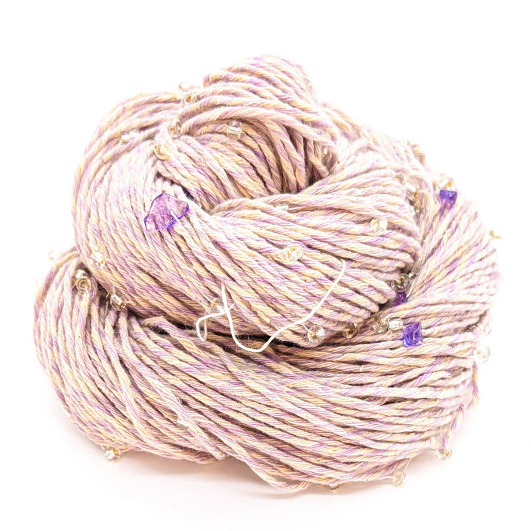 Coil of light pink and white twine with purple accents and transparent beads.