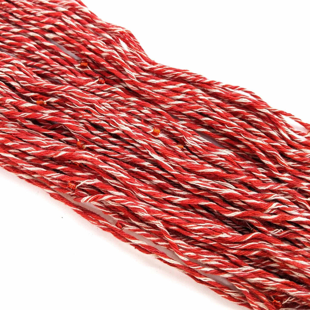 A bundle of twisted red and white polyester threads spread out on a white background.