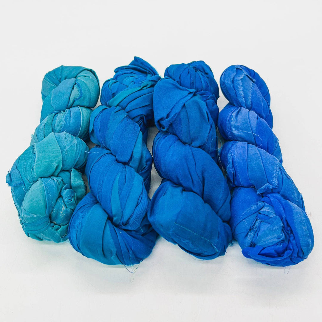 Five skeins of blue fabric yarn arranged in a row