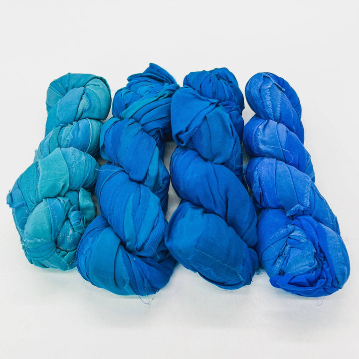 Five skeins of blue fabric yarn arranged in a row